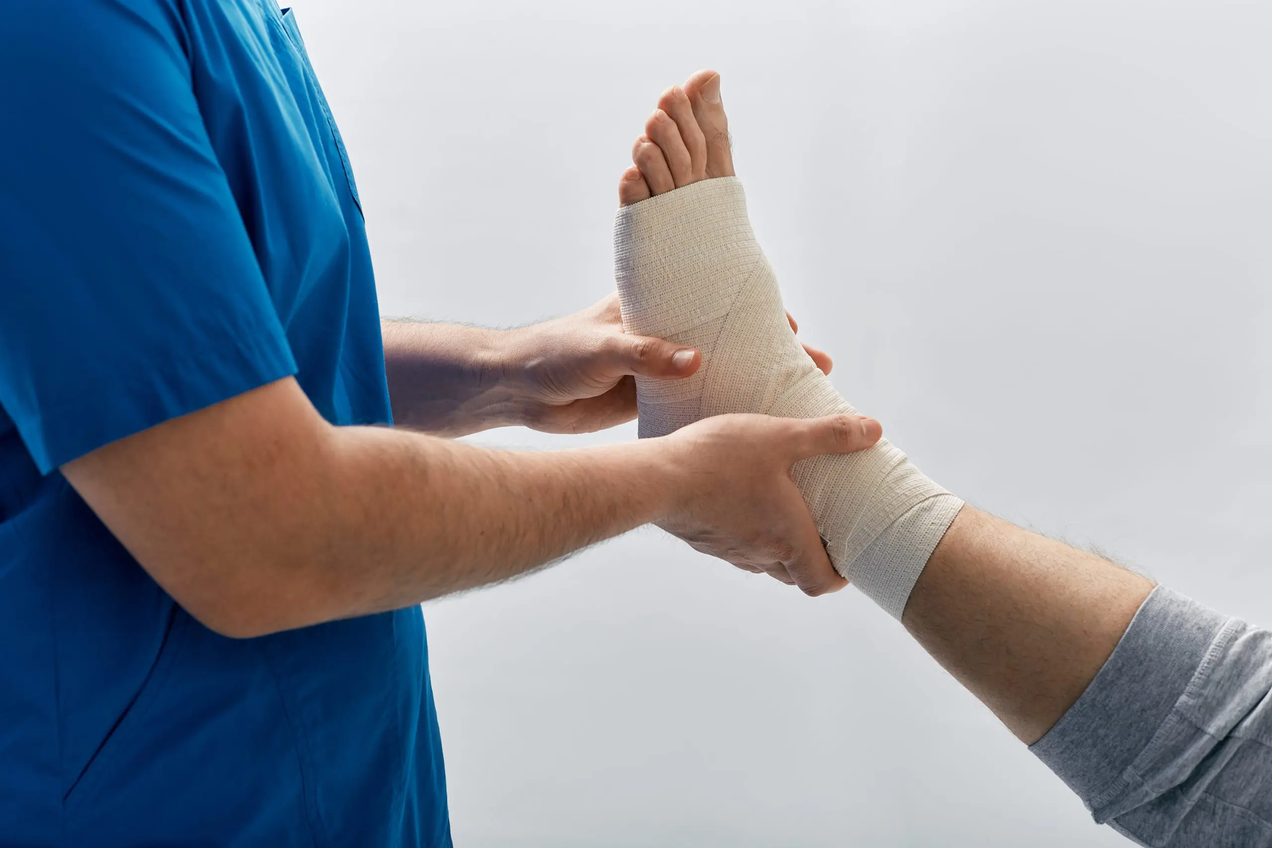 man in scrubs looking at a sprained ankle
