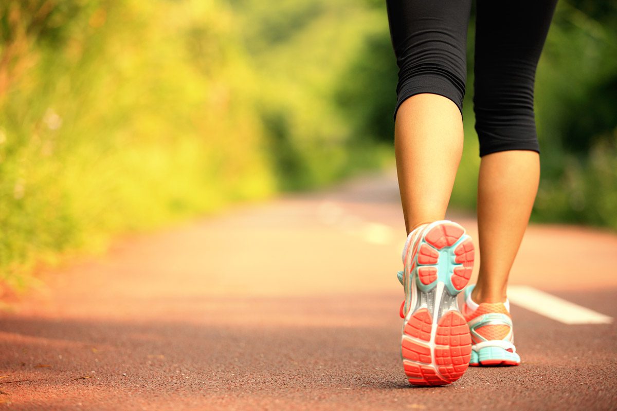 close-up shot of person's sneakers as they are walking on a park trail